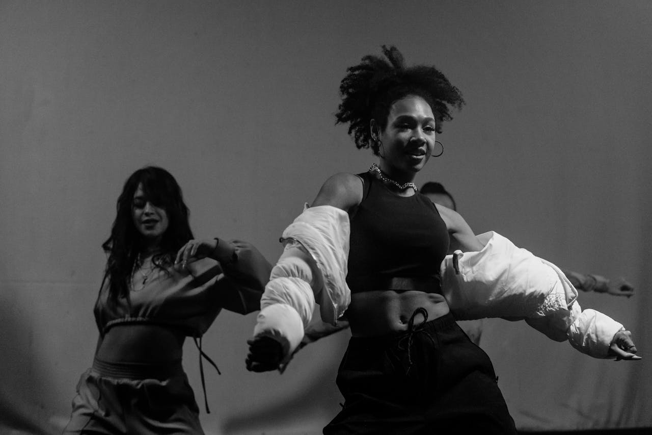 Captivating black and white photo of women dancing energetically indoors.